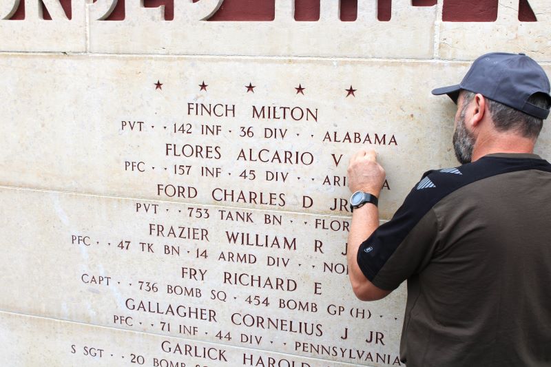 A staff member at Epinal American Cemetery places a rosette