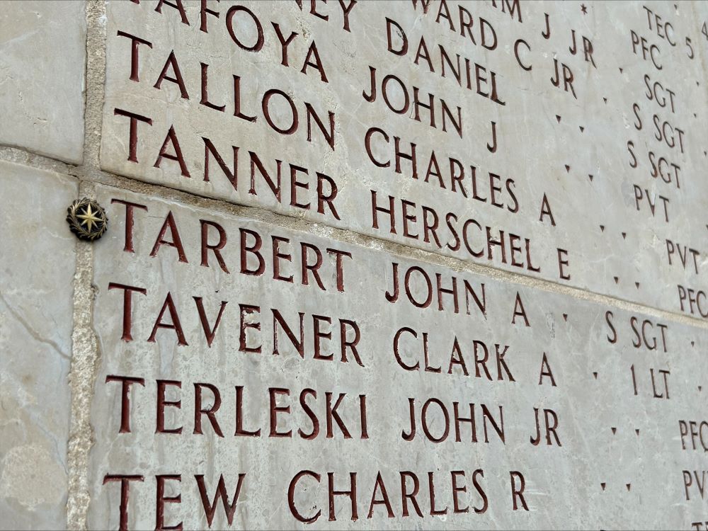 A bronze rosette is placed next to the name of John A. Tarbert on the Walls of the Missing