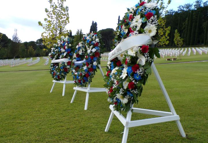 three wreaths on easels stand in front of the gravestones at Florence American Cemetery