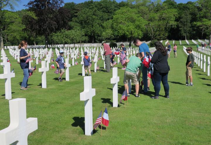 Men, women and children all work to place flags. 