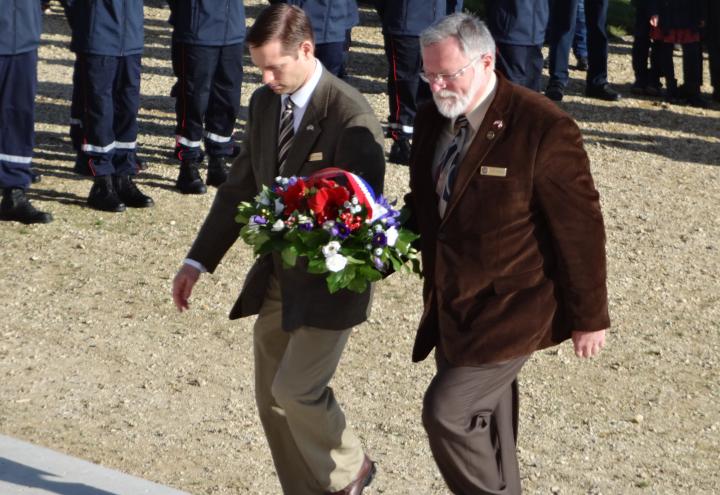 Cemetery staff walk up stairs towards the monument with flowers in hand. 