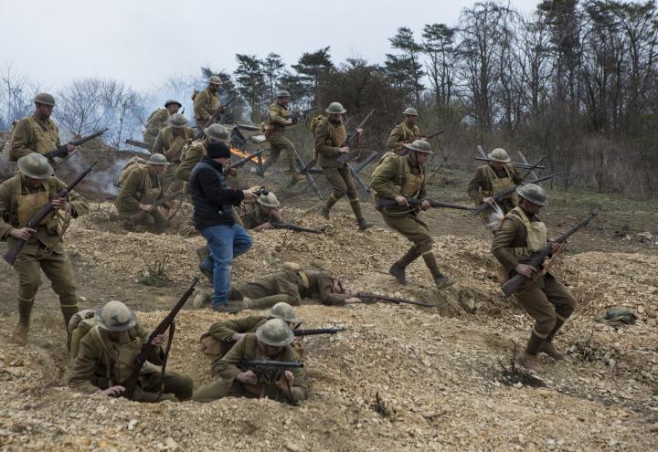 Men in WWI uniforms charge down a hill. 