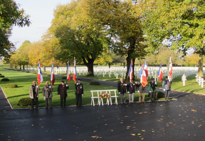 Men with flags flank the floral wreath that was laid on a stand. 