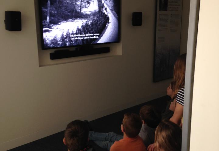 Young children sit on the floor and watch the new film. 