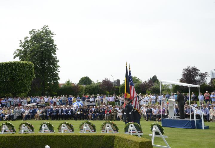 Attendees stand and sit while a man speaks from the podium.