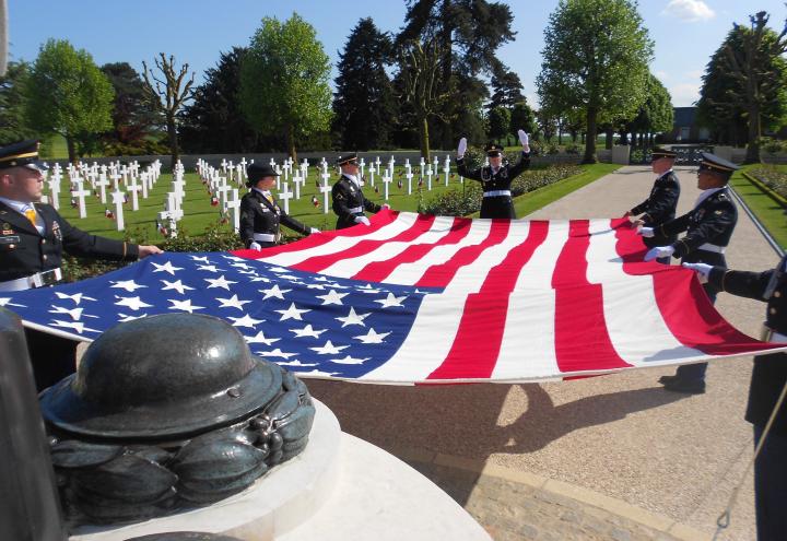 Members of the American military fold a large American flag. 