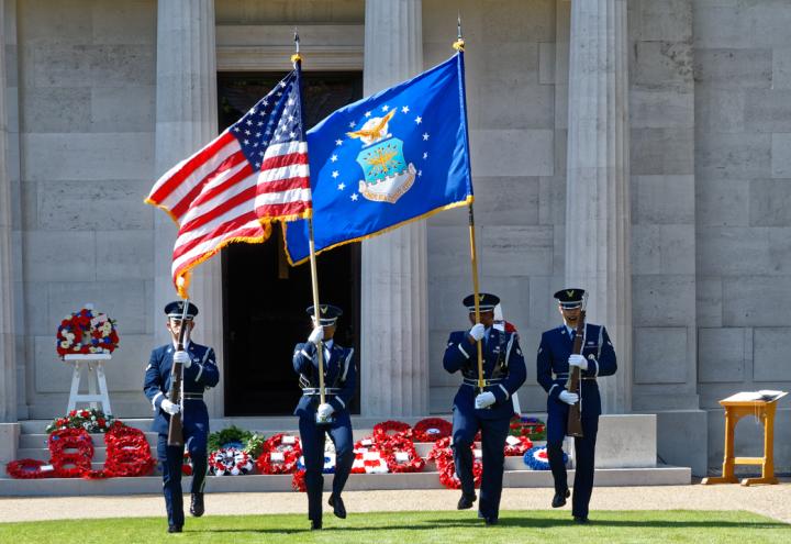 Men and women in uniform march with a flag or a firearm as part of the Honor Guard.