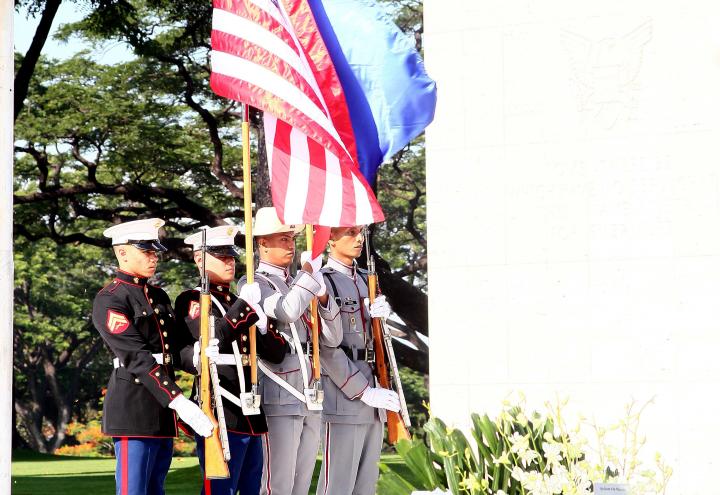 Men in uniform stand with flags. 