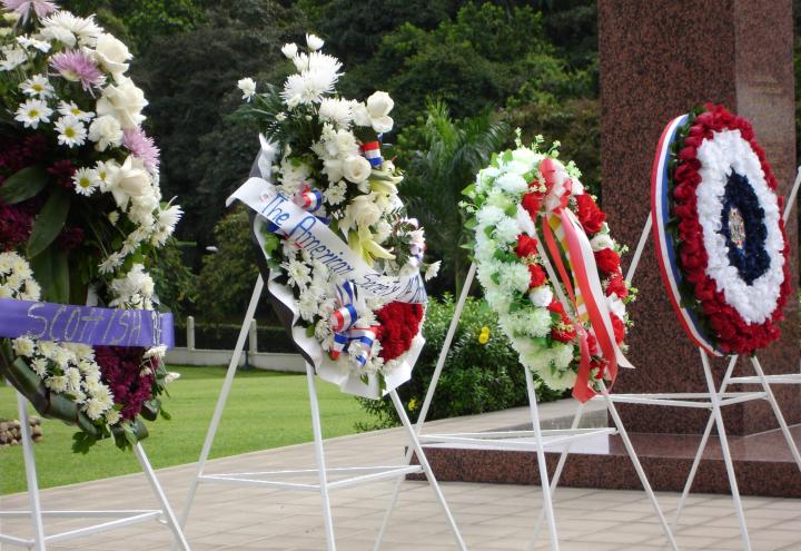 Four large floral wreaths rest on stands after the ceremony.