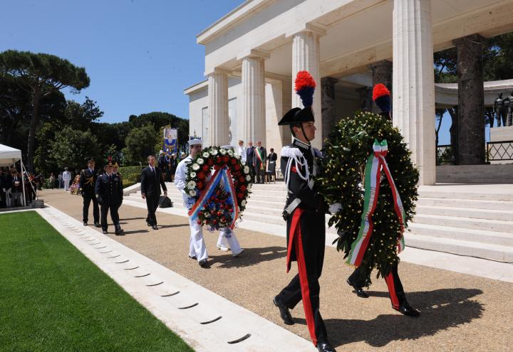 Members of the military carry floral wreaths. 