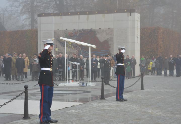 Marines salute as ceremony attendees look on. 