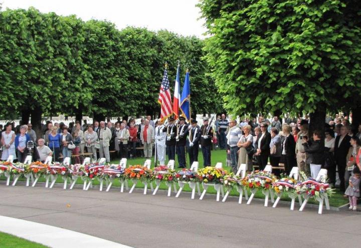 Attendees stand behind a line of floral wreaths. 