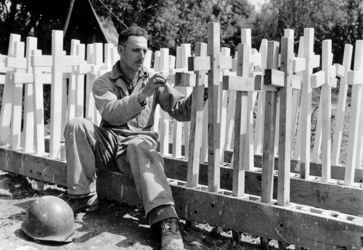 Historic photo shows soldier preparing wooden crosses.