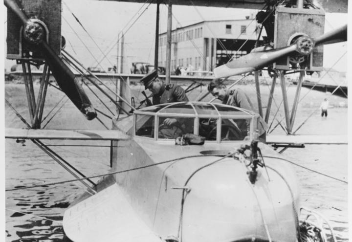 A historic photo showing a flying boat on the water outside the factory. 