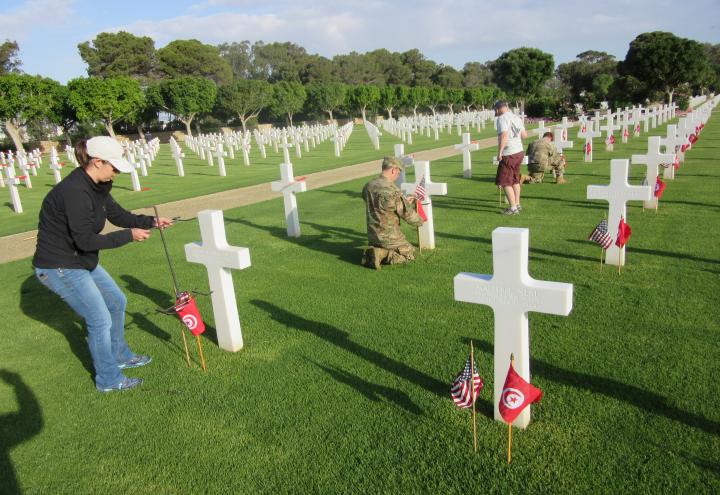 Volunteers place an American flag and Tunisian flag in front of every headstone. 