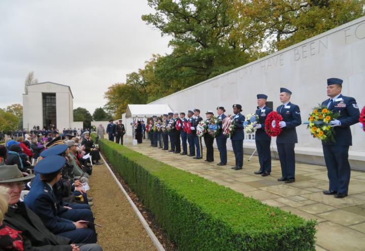 Men and women in uniform carry floral wreaths.