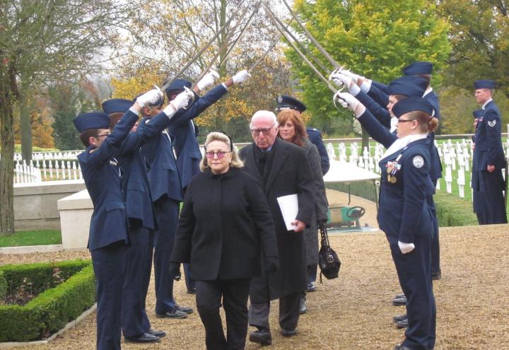 Four VIPs walk under sword-bearing men and women in uniform during 2012 Veterans Day ceremony.