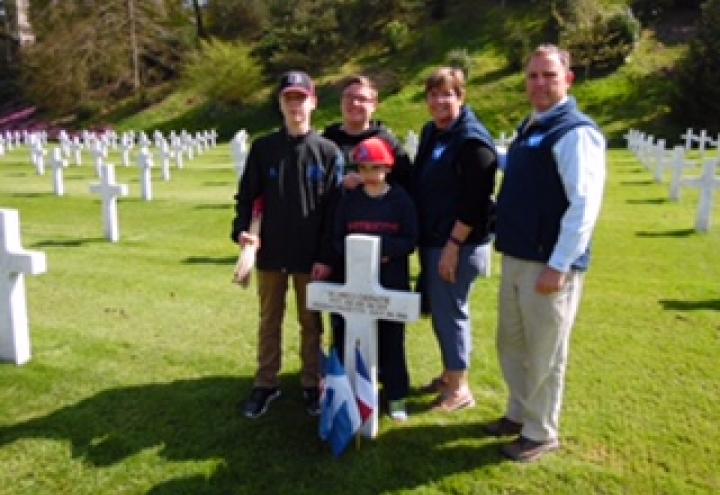 Family members stand behind a headstone in the cemetery. 