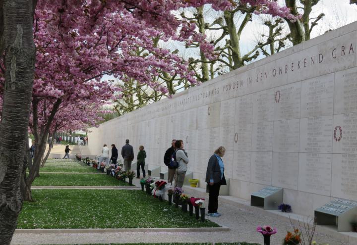 Visitors stand near the Walls of the Missing looking at photos. 