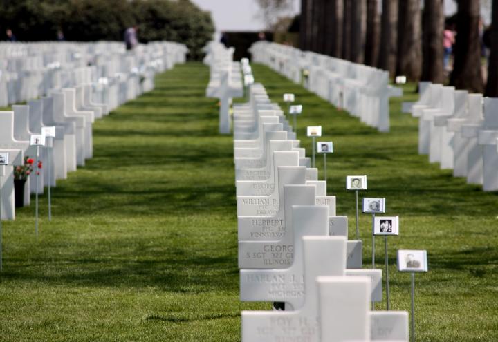 Photos on stands are next to the marble headstones.