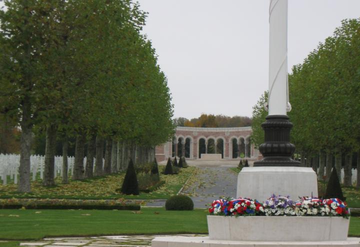 Wreaths lie at the base of a flag pole, with headstones and the chapel in the background, at Oise-Aisne American Cemetery for the 2012 Veterans Day ceremony.