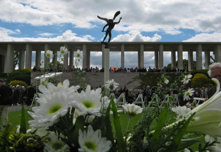 Blooming flowers with memorial and statue in background. 