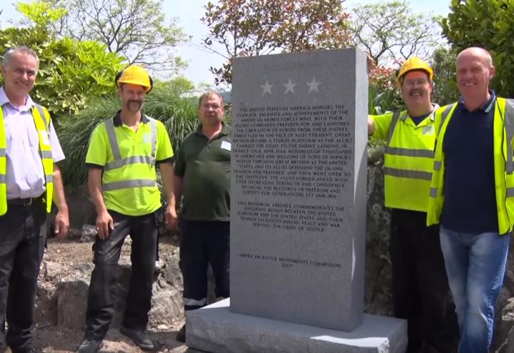 Men in construction gear stand next to the new memorial. 