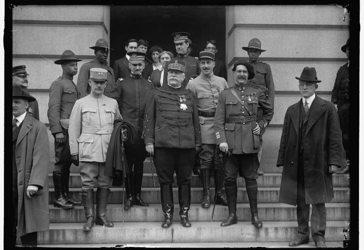 Men in uniform stand on the steps outside the building. 