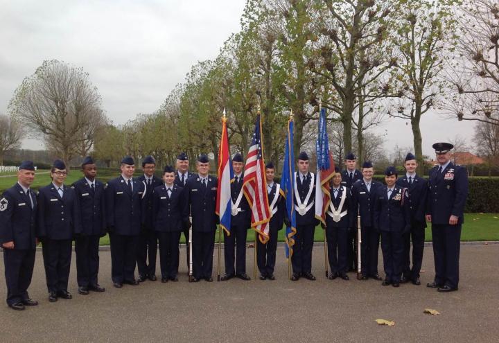 JROTC participants stand in uniform with flags