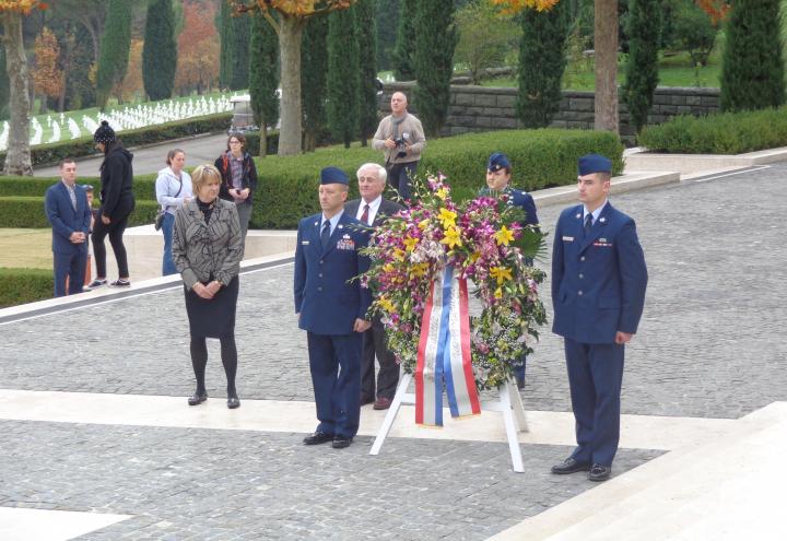 Commissioner Klass and Maj. Martin stand next to a large floral wreath. 