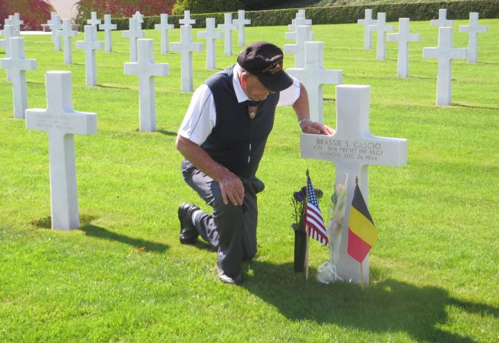 Merritt kneels next to the gravesite of Cpl. Brassie S. Cascio. 