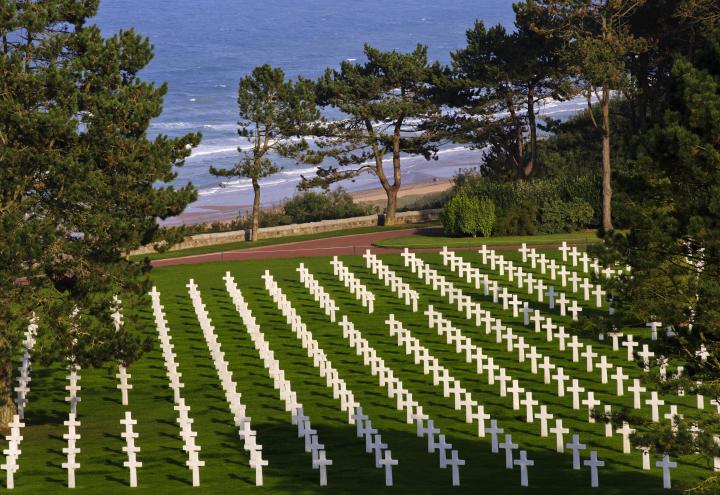 Rows of marble headstones dot the landscape with the English Channel in the background.