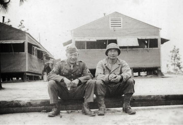 Historic image showing Victor and Johnny in uniform sitting on curb. 