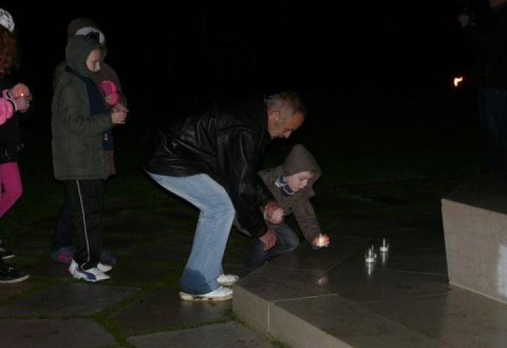 A man and child place candles at the base of the flag pole. 