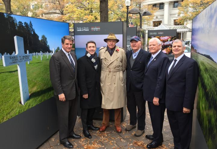 Men stand in front of large photo displays. 