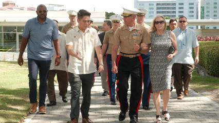 Vicente Lim IV (Vincci) Manila Visitor Center Director and U.S. Marine Commandant walking together, accompanied by others, outdoors at Manila American Cemetery.