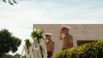 Commandant of the Marine Corps General Eric M. Smith and Sergeant Major of the Marine Corps Carlos A. Ruiz saluting at the Sept. 11, 2024, wreath-laying ceremony outside at Manila American Cemetery with the backdrop of a simple monumental building and blue sky. 