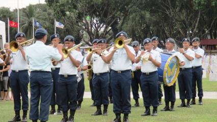Members of the band in uniform stand in rows as they play. 