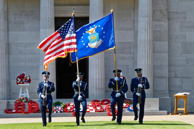 Men and women in uniform march with a flag or a firearm as part of the Honor Guard.